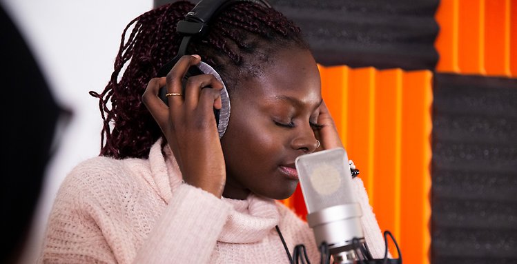 Sångerska sjunger i studio med hörlurar
